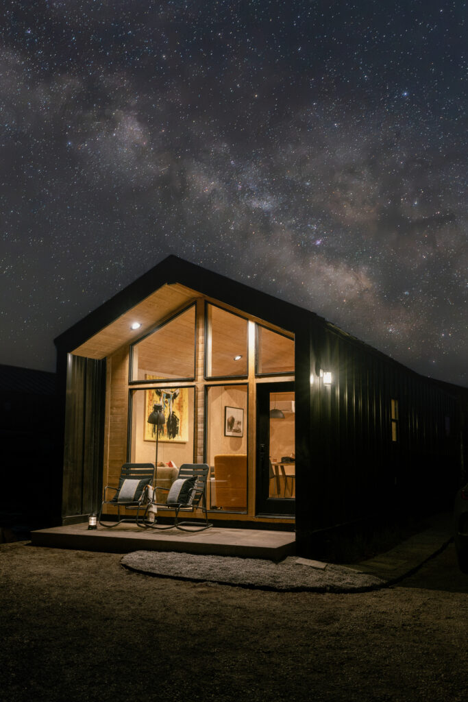 Yellowstone Peaks cabin at night in Island Park, Idaho, glowing under the Milky Way sky, photographed by Josi Frommelt.
